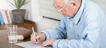 Ein ältere Mann löst ein Kreuzworträtsel