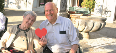 Deux personnes âgées sourient et tiennent un cœur