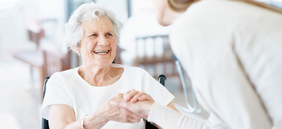 Eine ältere Frau schüttelt eine Hand und lächelt