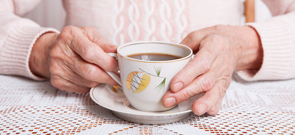 Eine ältere Frau hält eine Tasse Kaffee