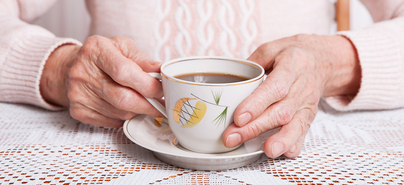 Eine ältere Frau hält eine Tasse Kaffee