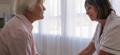 Aufmerksames Gespräch zwischen Frau mit Demenz und Pflegerin