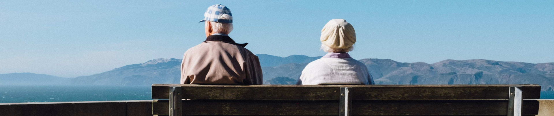 Mann mit Demenz sitzt mit seiner Frau auf einer Bank