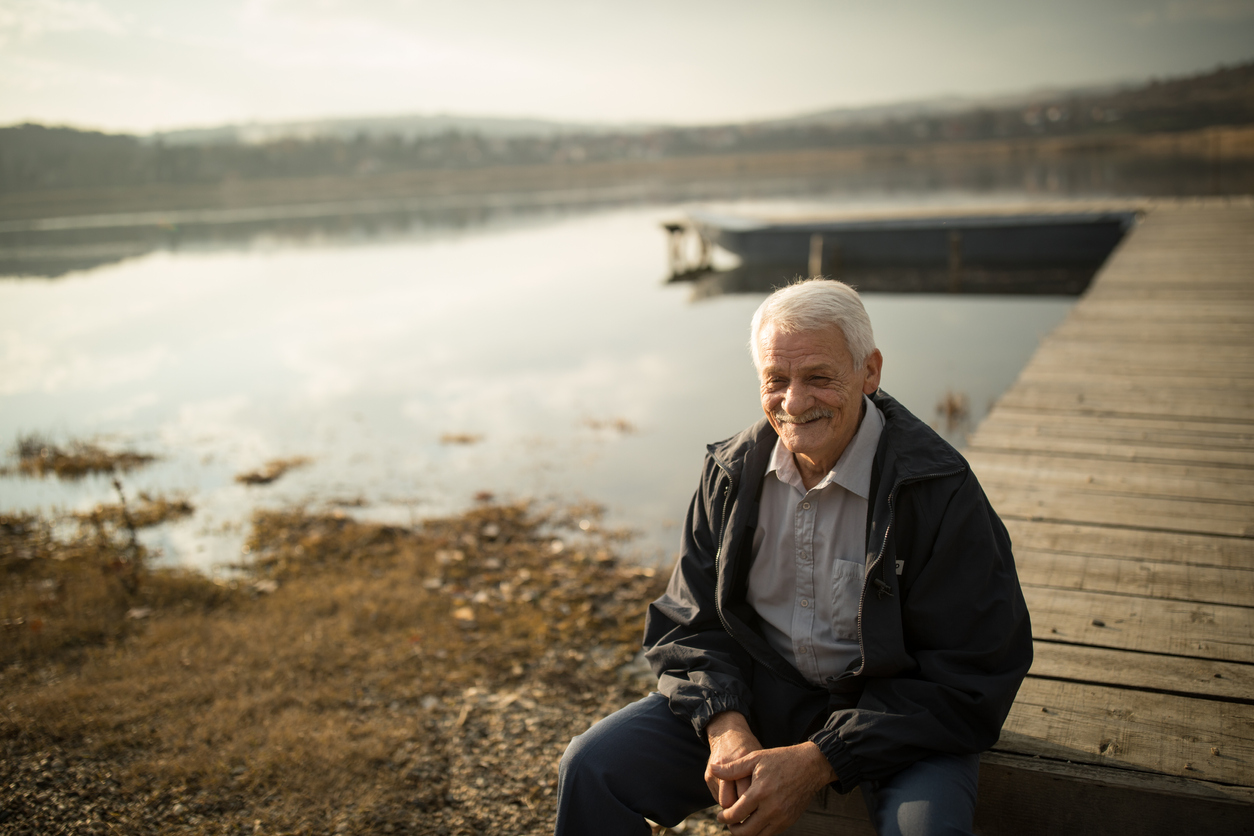 Ein glücklicher Mann sitzt am Seeufer